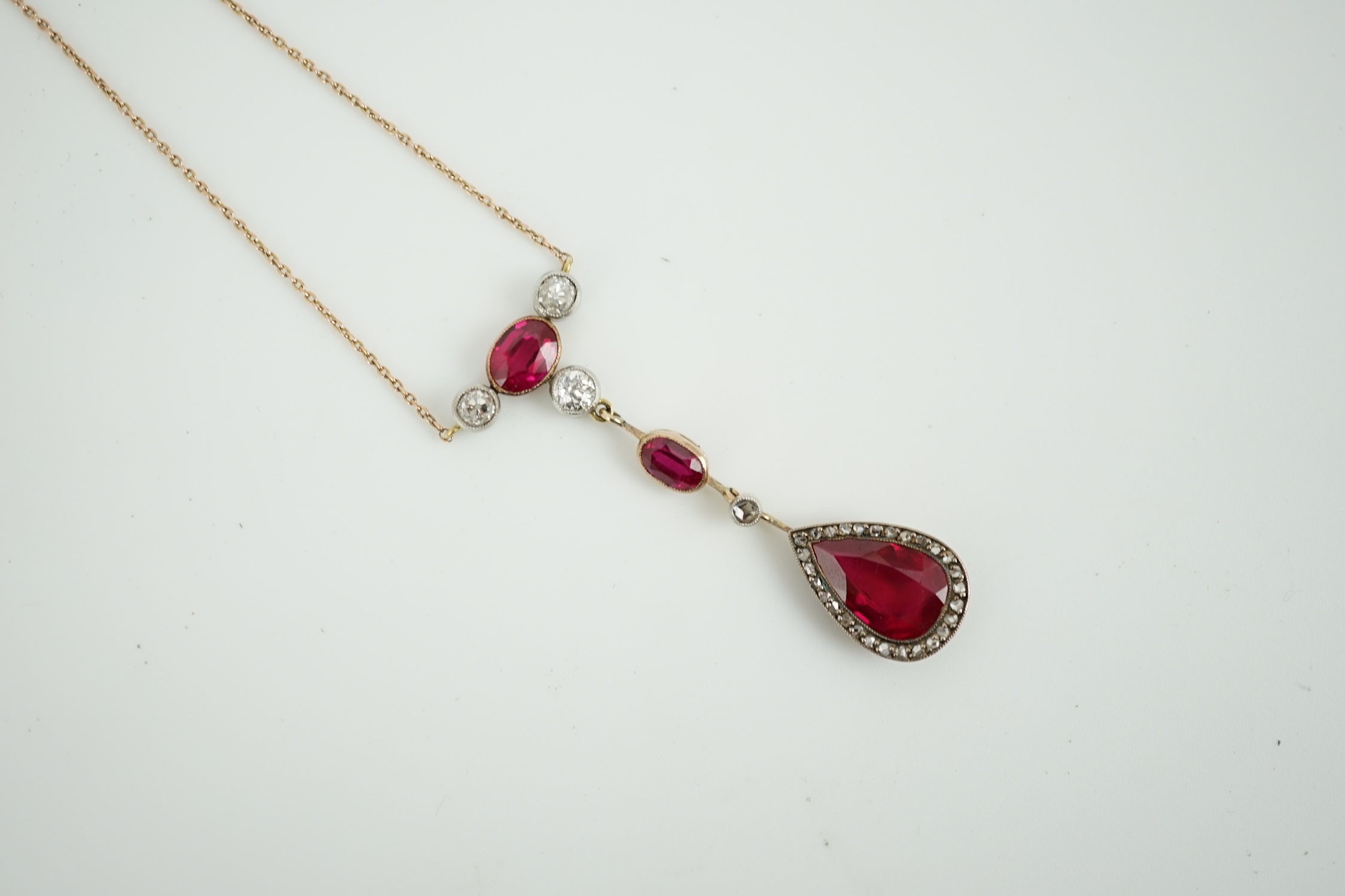 A 9ct, three stone synthetic ruby and four stone diamond set drop pendant necklace, pendant section 49mm, gross weight 5.2 gram.